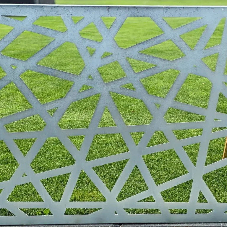 Ażurowy panel z geometrycznym wzorem ustawiony na świeżo skoszonej trawie.