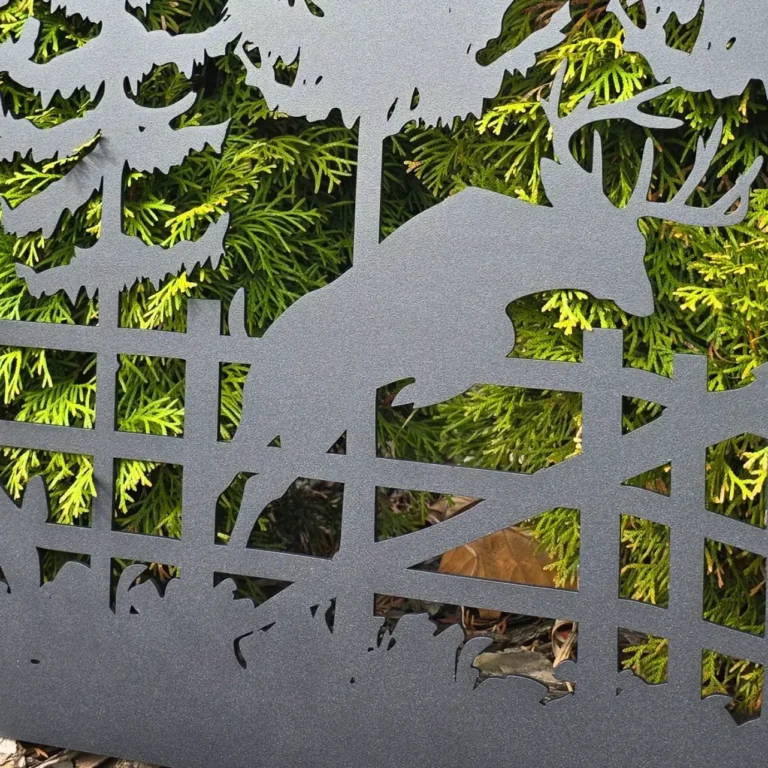 Metalowy panel z wyciętym motywem jelenia skaczącego przez płot na tle drzew.